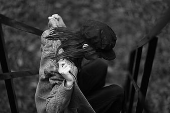 Woman in cap and coat sitting on outdoor stairs