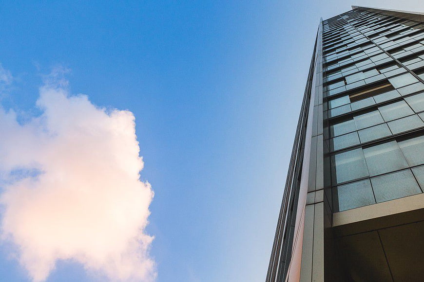 Modern Glass Skyscraper Against Blue Sky with Clouds