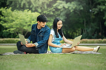 Young Asian couple studying with laptops in a park
