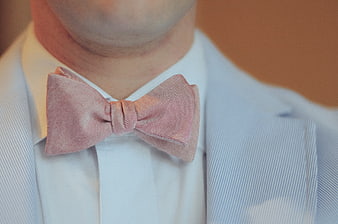 Close-up of man wearing pink herringbone bow tie and blue suit
