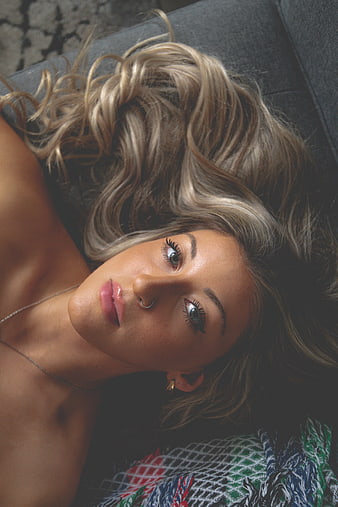 Close-up portrait of blonde woman lying down with nose ring