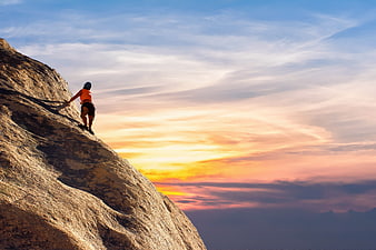 Rock Climber Scaling Mountain Cliff at Sunset