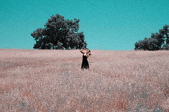 Woman in black dress standing in dry grass field