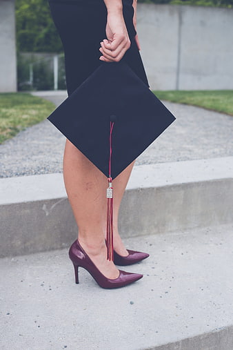 Woman holding graduation cap with red tassel and heels