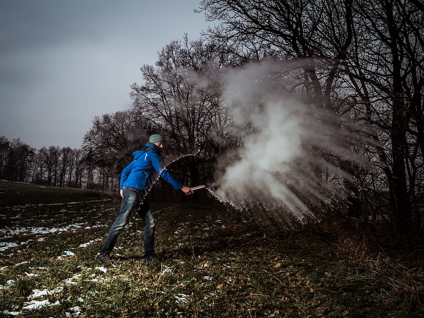 Man Creating Mpemba Effect Steam in Winter Forest