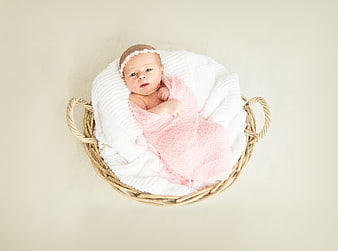 Newborn baby girl in wicker basket with pink wrap