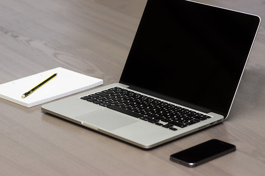 Minimalist workspace with laptop, smartphone, and notebook on wooden desk