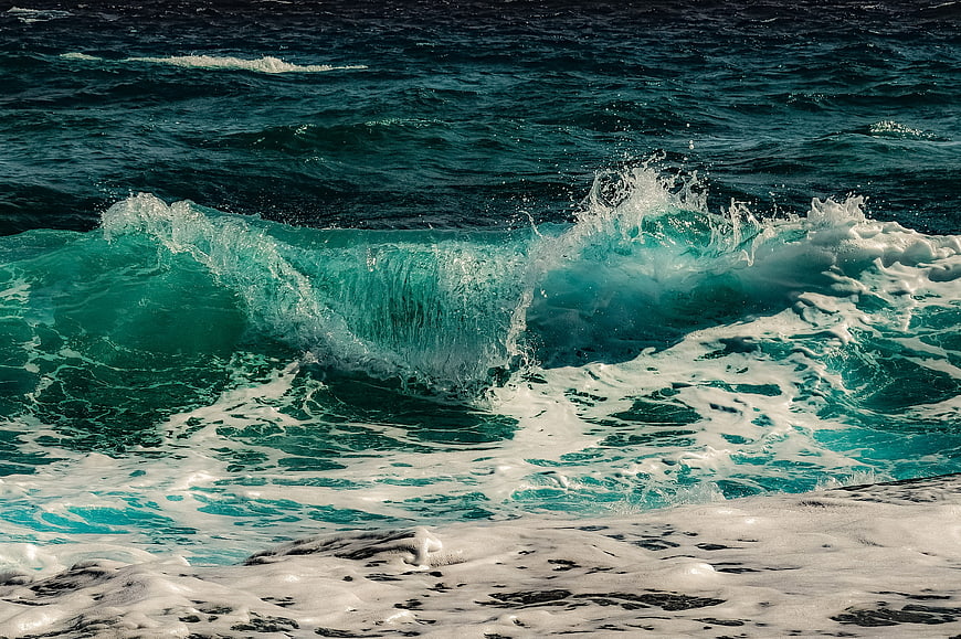 Powerful turquoise ocean wave crashing with white sea foam