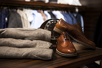 Brown leather brogues and folded grey sweater on wooden table