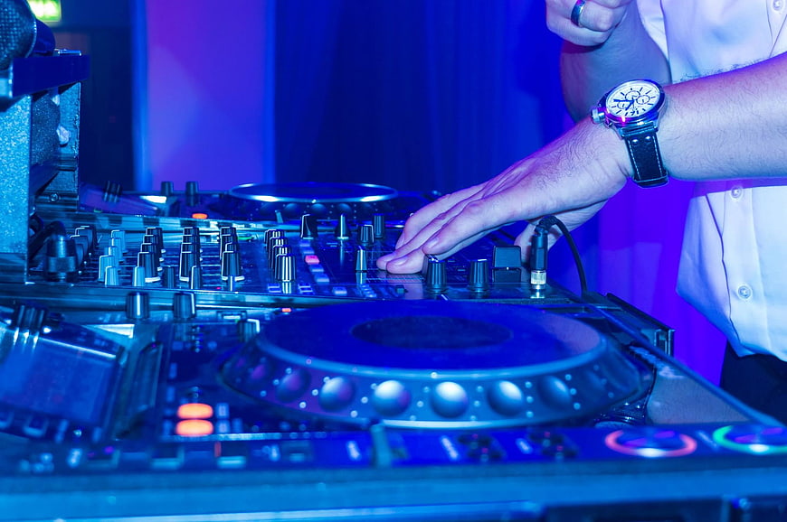 DJ Hands Mixing on Turntables in Blue Club Lighting