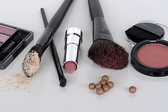 Flat lay of makeup brushes, lipstick, and blush on white background