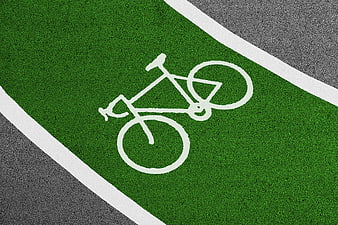 Green bicycle lane with white bike symbol on asphalt road