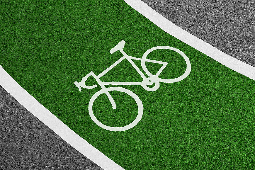 Green bicycle lane with white bike symbol on asphalt road