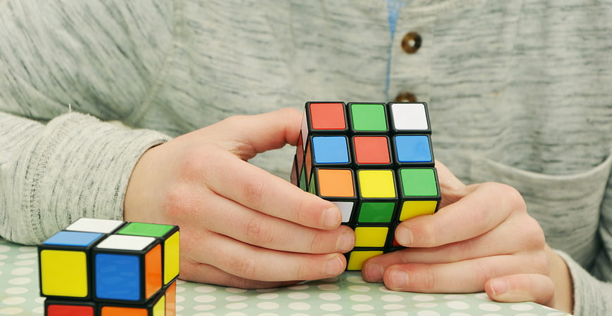 Child hands solving colorful Rubik's cube puzzle