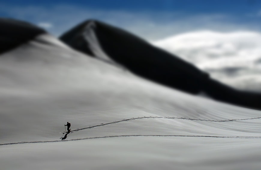 Lone Hiker Silhouette on Snowy Mountain Slope