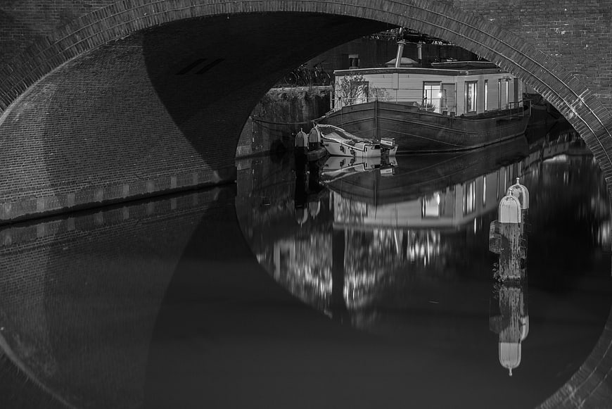 Black and White Canal Boat Under Brick Arch Bridge