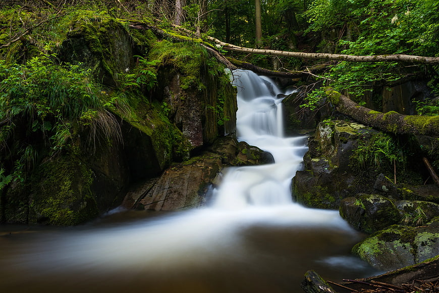 Misty waterfall cascading through lush green forest rocks