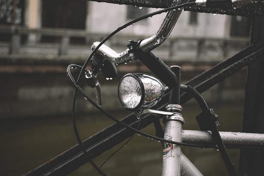 Close-up of wet vintage bicycle handlebars and headlight in rain