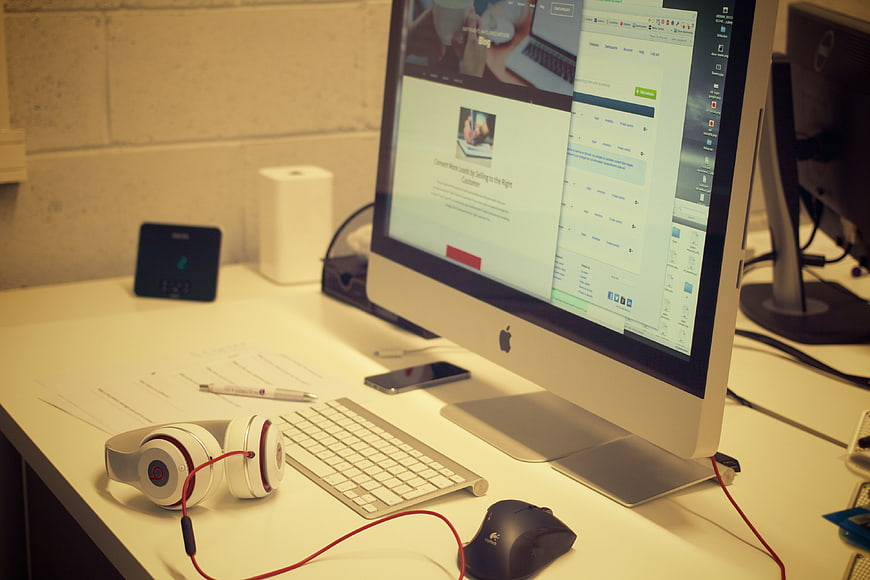 Modern office desk with iMac, headphones, and workspace essentials
