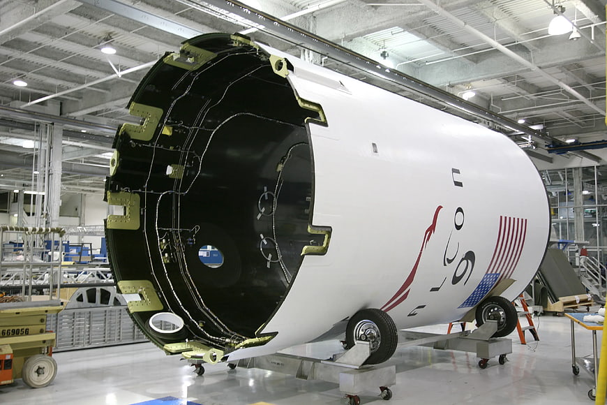Unfinished rocket fuselage with US flag in aerospace factory