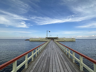 Wooden pier extending into the ocean with a building at the end