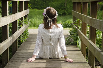 Woman in White Lace Dress Sitting on Wooden Bridge