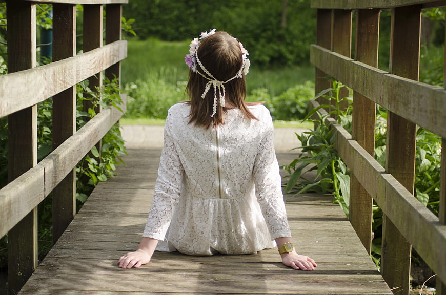 Woman in White Lace Dress Sitting on Wooden Bridge