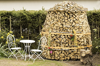 Rustic firewood stack with white garden furniture in backyard