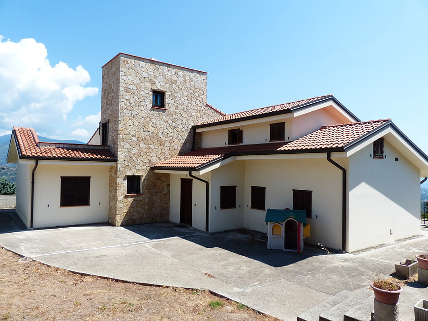 Modern white house with stone facade and red tile roof