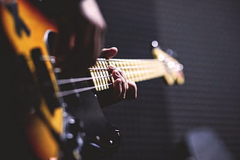 Close-up of hands playing electric bass guitar on stage