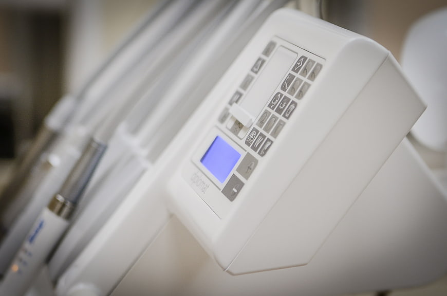 Close-up of white dental equipment control panel with blue screen