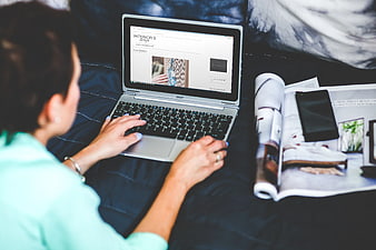 Woman browsing interior design website on laptop in bed