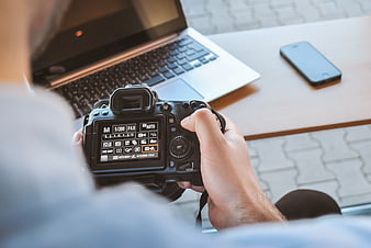 Over-the-shoulder view of photographer adjusting DSLR camera settings