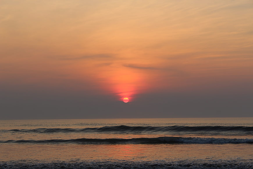 Serene Sunset Over Ocean Waves with Golden Sky Reflection