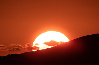 Vibrant Orange Sunset Behind Silhouetted Mountain Ridge