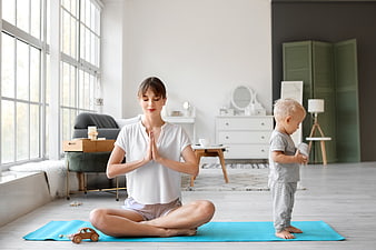 Mother meditating with toddler in bright living room