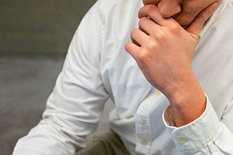 Close-up of man in white shirt holding chin in thought