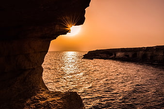 Sunset Starburst Through Sea Cave Arch Over Ocean