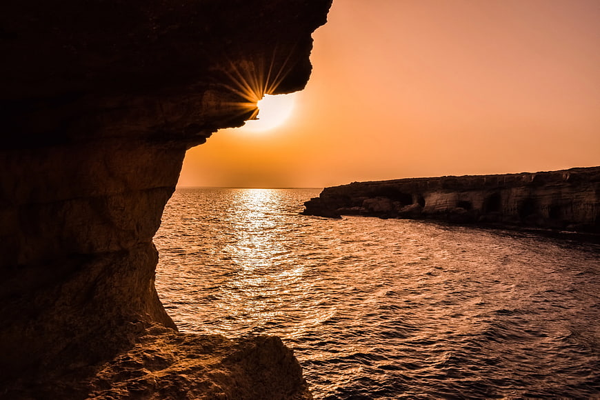 Sunset Starburst Through Sea Cave Arch Over Ocean