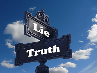 Street sign pointing to truth and lie against blue sky