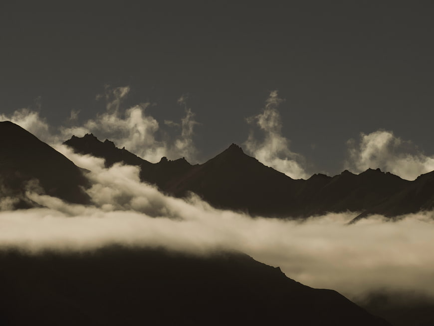 Dramatic mountain silhouette with clouds and dark sky