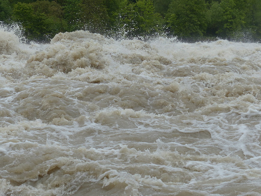 Powerful muddy floodwaters churning with white foam and splashes