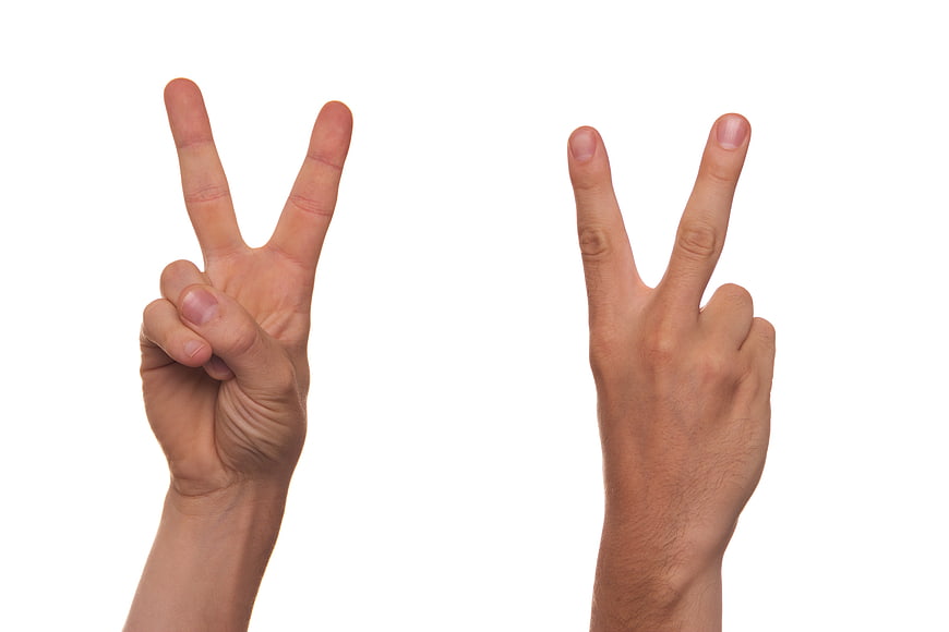 Two male hands making peace sign against white background