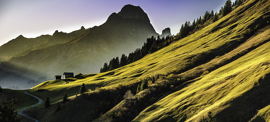 Sunlit Alpine Mountain Landscape with Rolling Green Hills