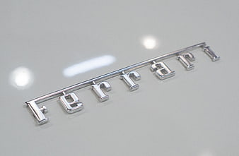 Close-up of chrome Ferrari emblem on white car surface