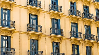 Yellow building facade with blue shutters and balconies