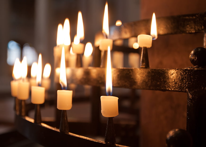 Lighted candles on a metal stand in a church interior
