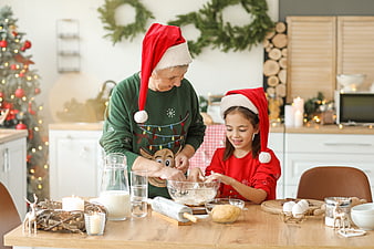 Grandmother and granddaughter baking Christmas cookies in festive kitchen