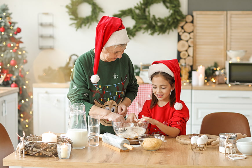 Grandmother and granddaughter baking Christmas cookies in festive kitchen