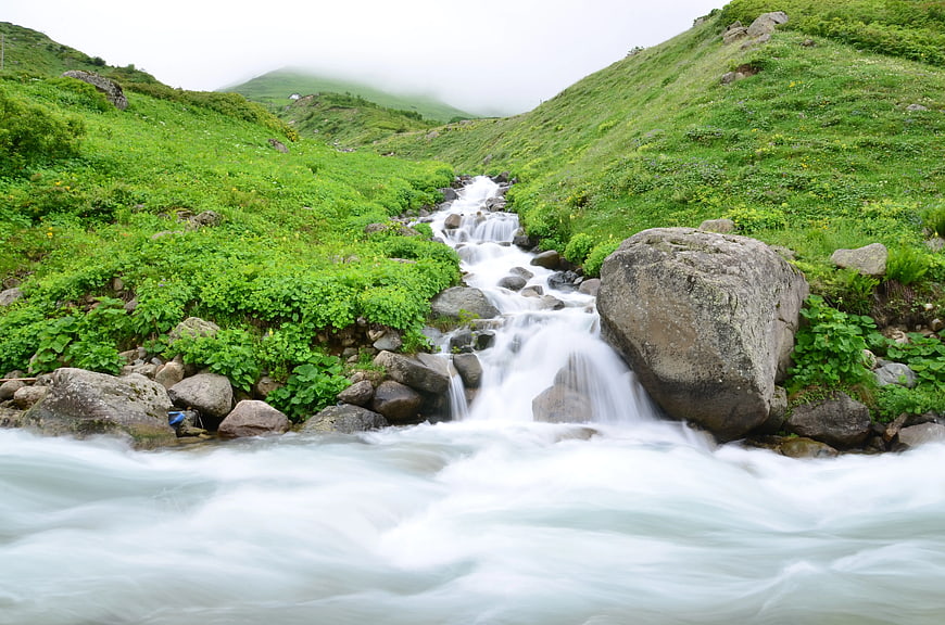 Flowing Mountain Stream Through Lush Green Valley